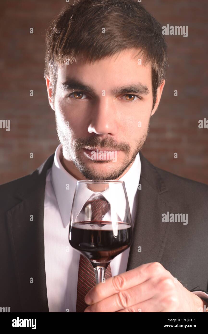 Man sniffing red wine in glass on brick wall background Stock Photo - Alamy