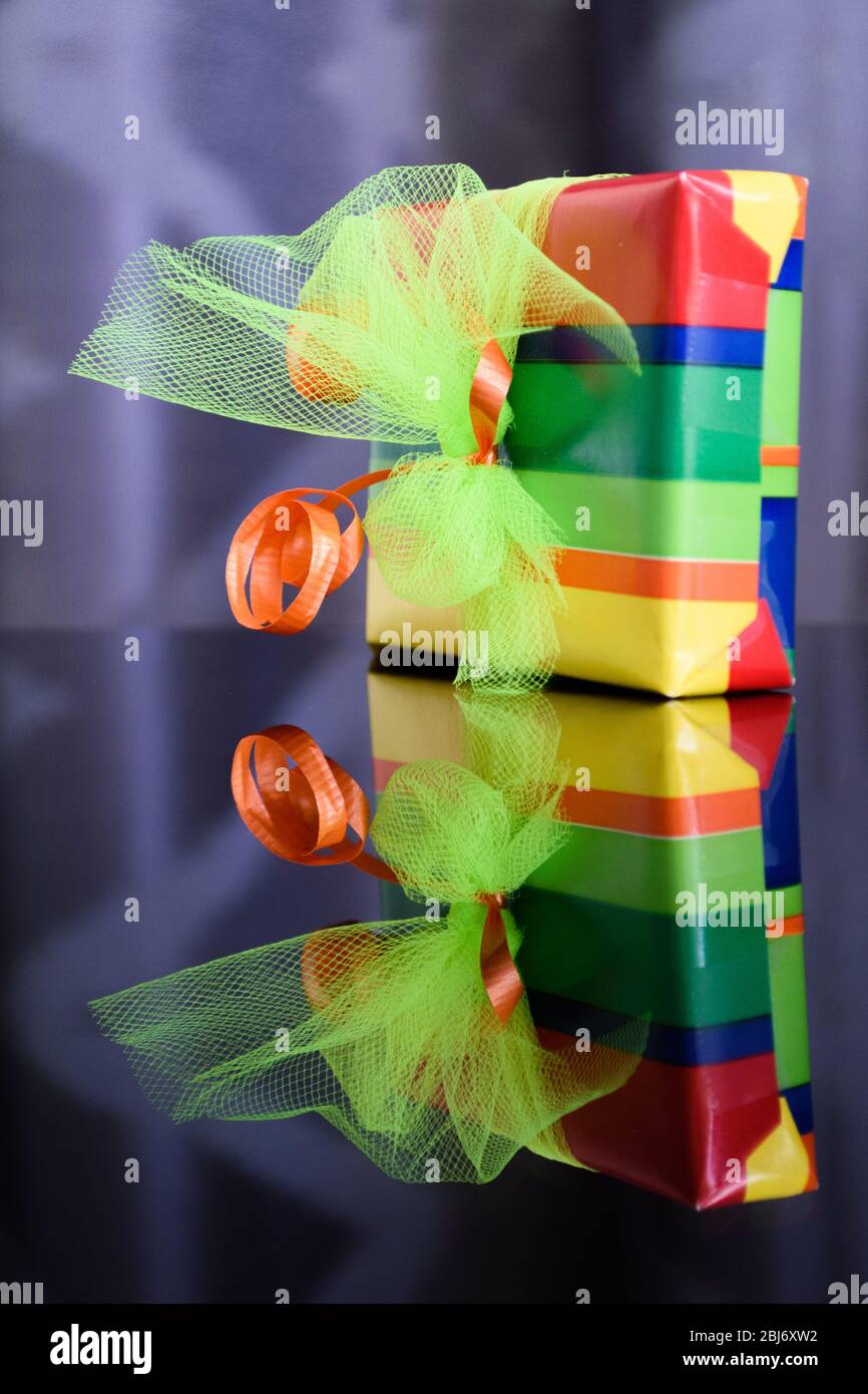 Bright and colourful gift box reflected in the glass table below Stock Photo