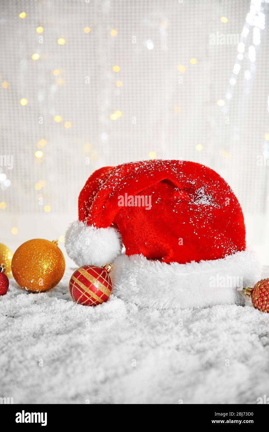 Santa Claus hat with toys on a snowy table over glitter background ...
