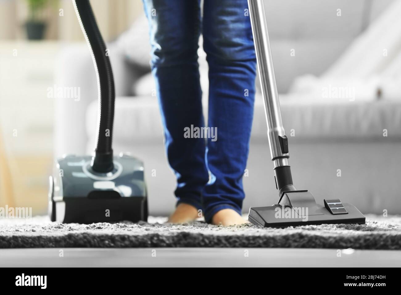 Woman cleaning the carpet with vacuum cleaner in the living room Stock ...