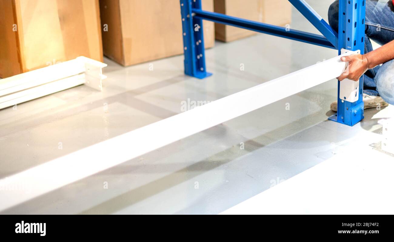 Male hand preparing to assembling the metal rack  in in warehouse or storage and shelves for cardboard boxes of products. Stock Photo