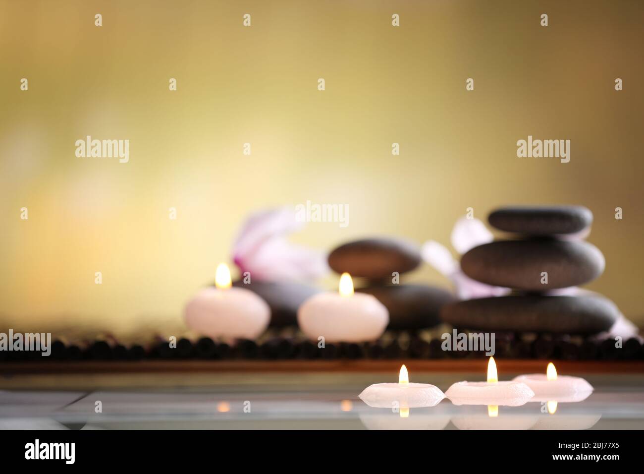 Spa still life with stones, candles and flowers in water on blurred ...