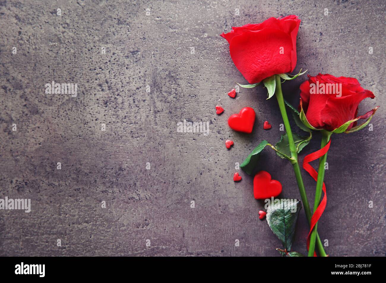 Beautiful red rose with small hearts on grey textured background Stock ...
