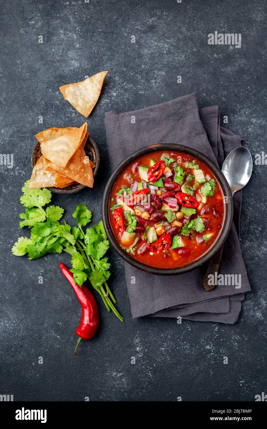 Mexican black bean tomato soup in clay bowl. Gray background Stock