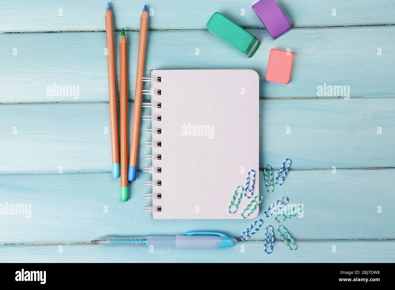 Office set with notebook, colored pencils and erasers on blue background Stock Photo