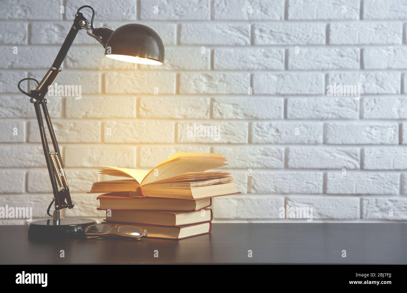 Modern lamp and books on the desk on white wall background Stock Photo ...