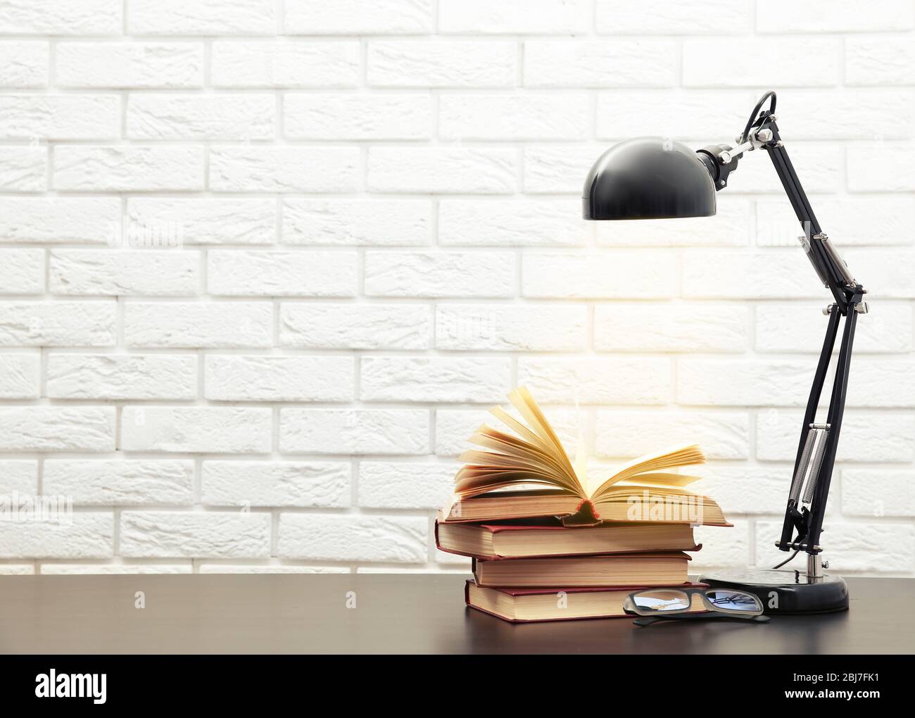 Modern lamp and books on the desk on white wall background Stock Photo ...
