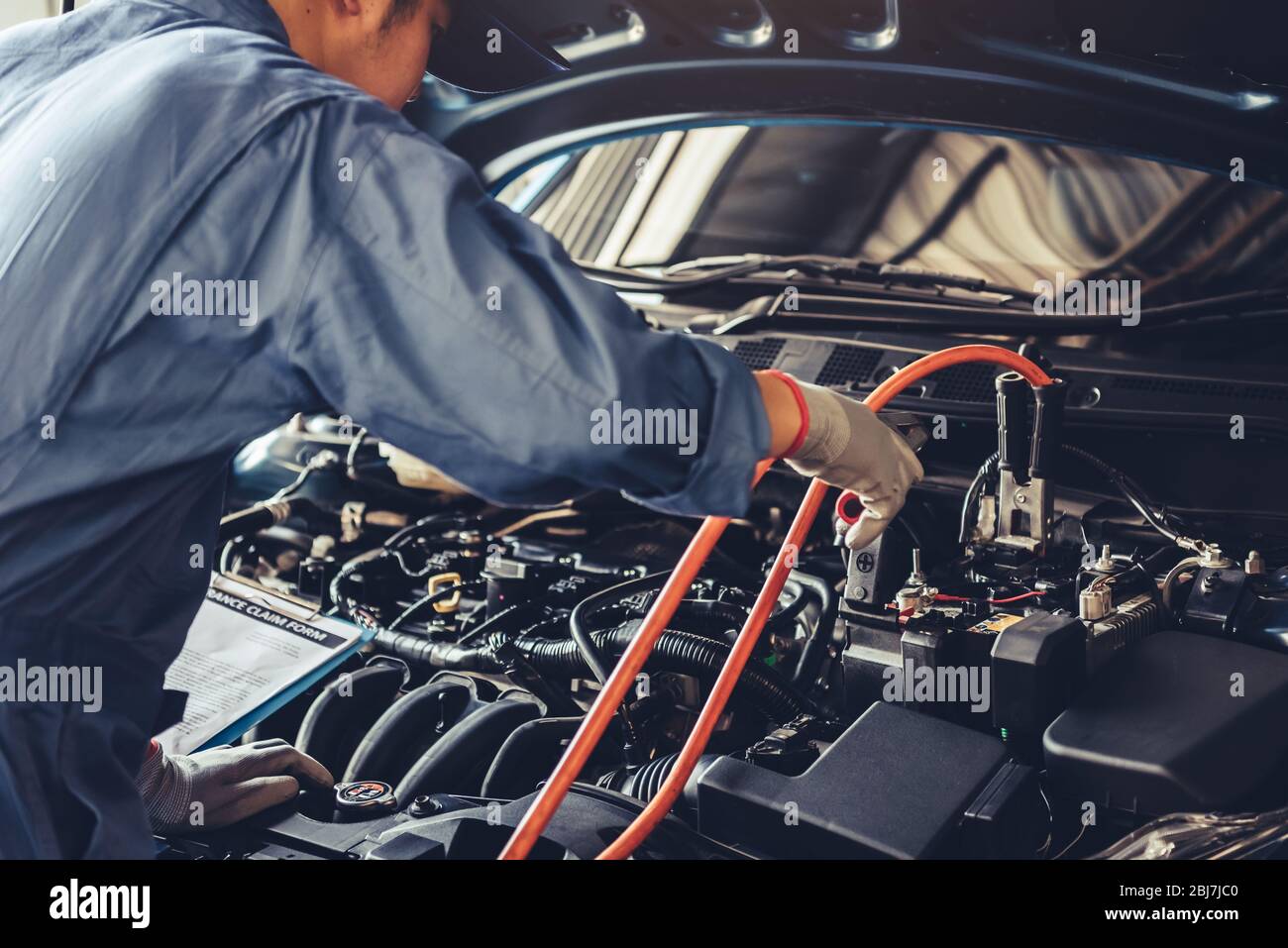 Car mechanic holding battery electricity trough cables jumper and