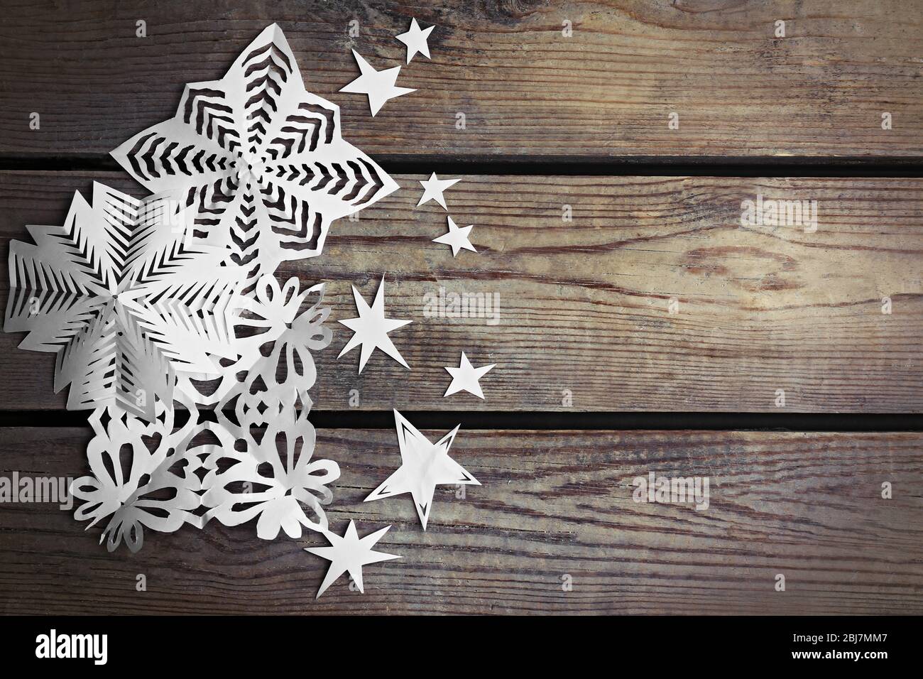 Winter background with hand-made paper snowflakes on wooden background Stock Photo