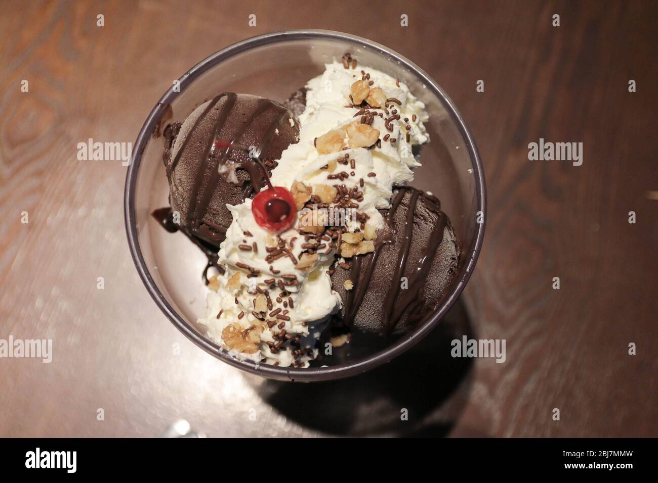 Top view image of Chocolate ice cream in a bowl with whipping cream and cherry on top Stock Photo