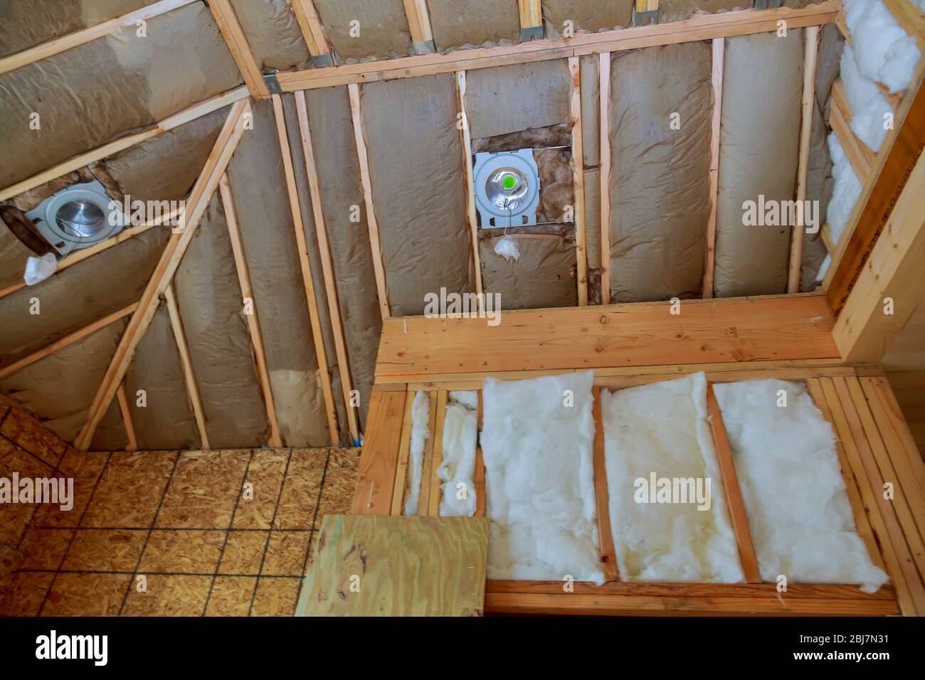 New frame house of fiberglass cold barrier insulation material in the sloping attic Stock Photo