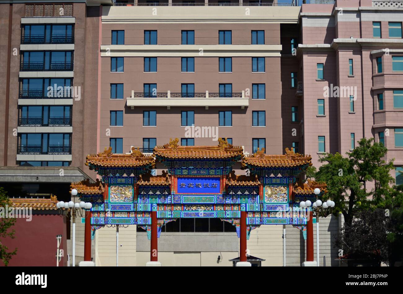 Traditional chinese archway in front of a modern building. Qianmen East Street, Beijing. China Stock Photo
