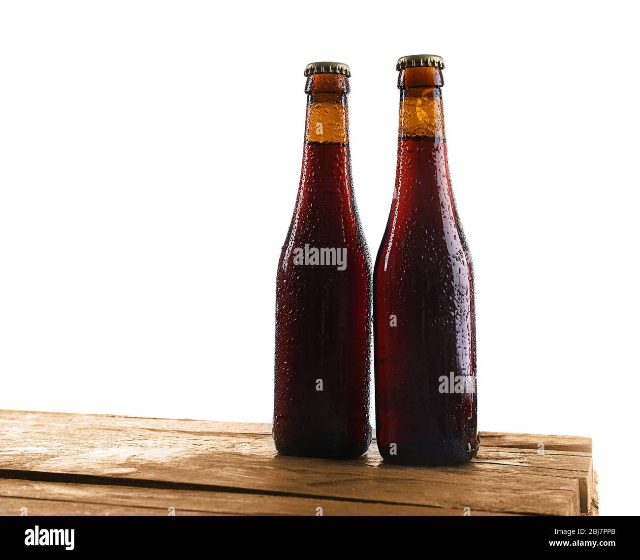 Unlabeled beer bottles on wooden table against white background Stock