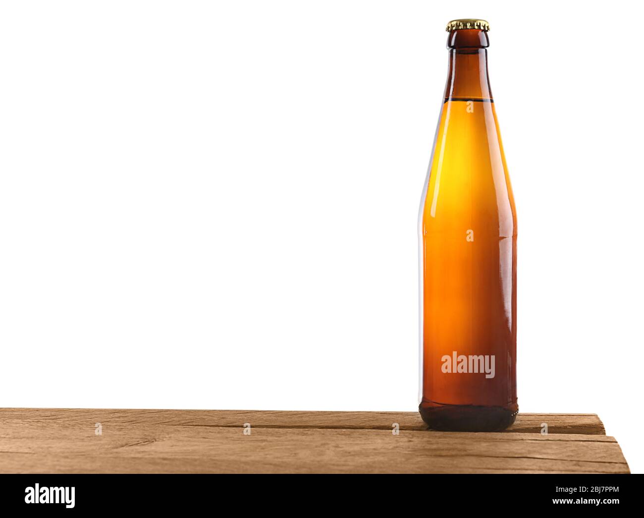 Unlabeled beer bottle on wooden table against white background Stock