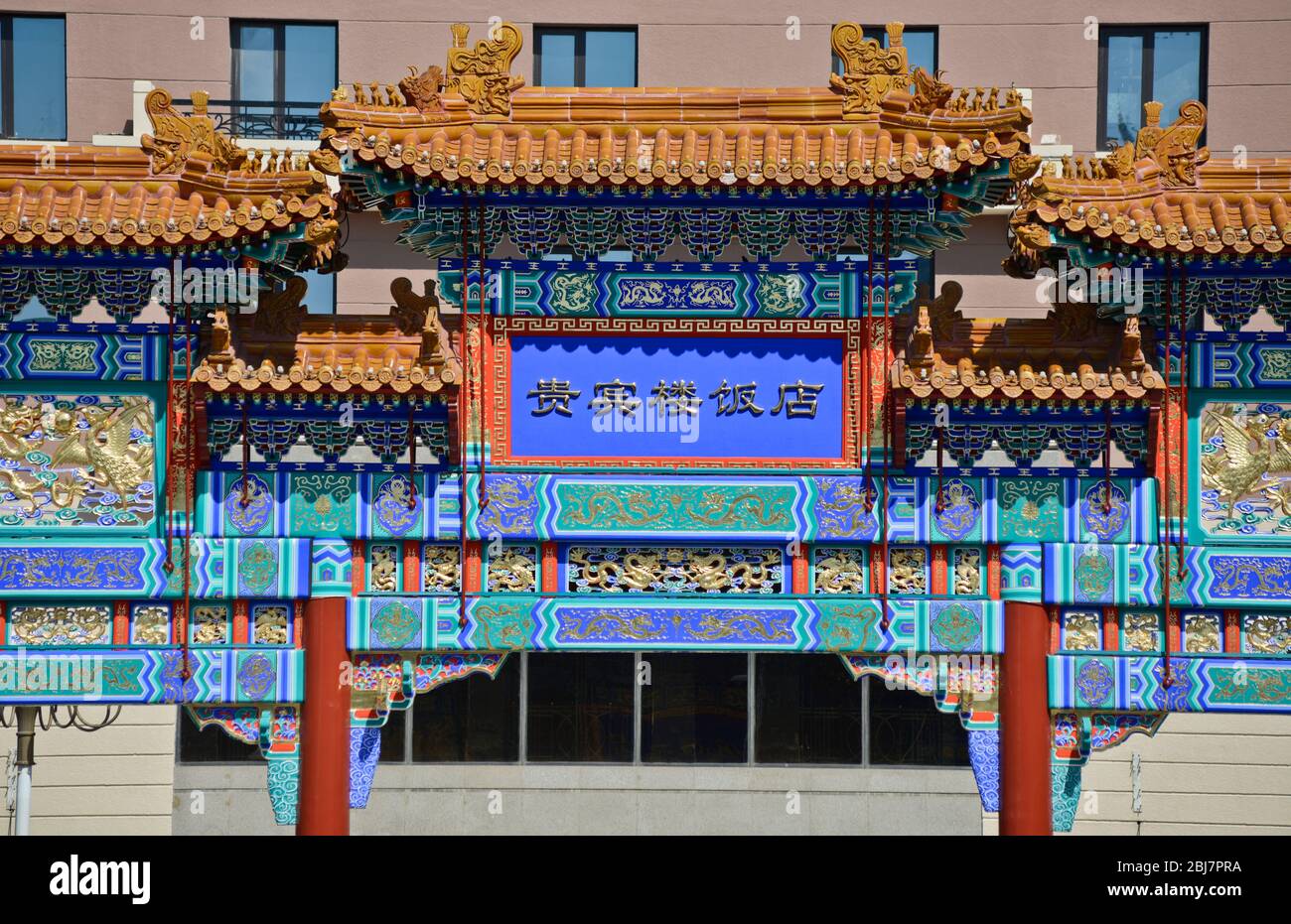 Traditional chinese archway in front of a modern building. Qianmen East Street, Beijing. China Stock Photo