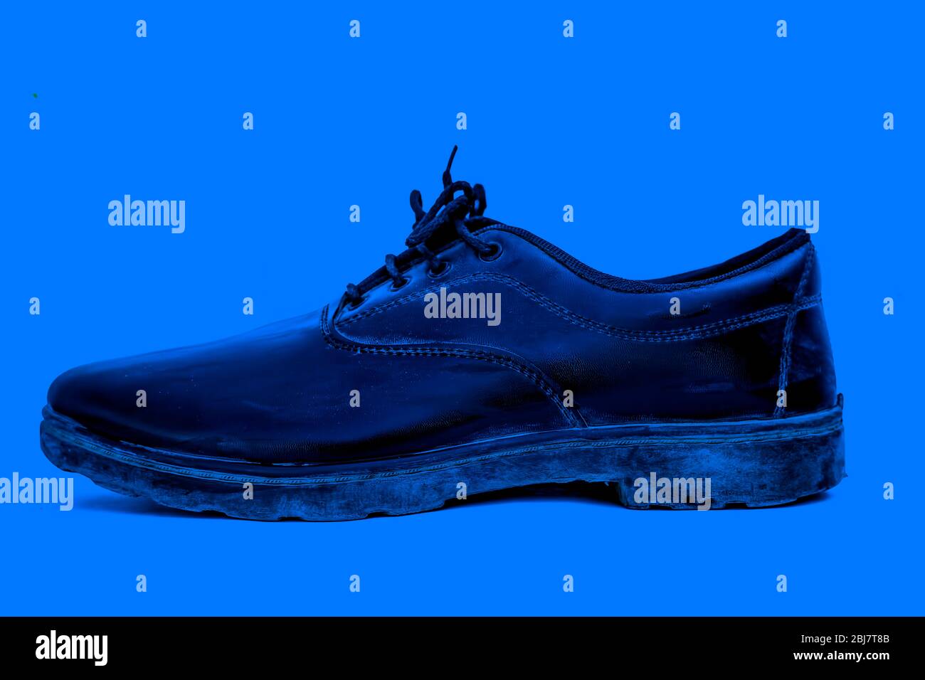 Close up shot of black colored school shoe isolated on a blue colored
