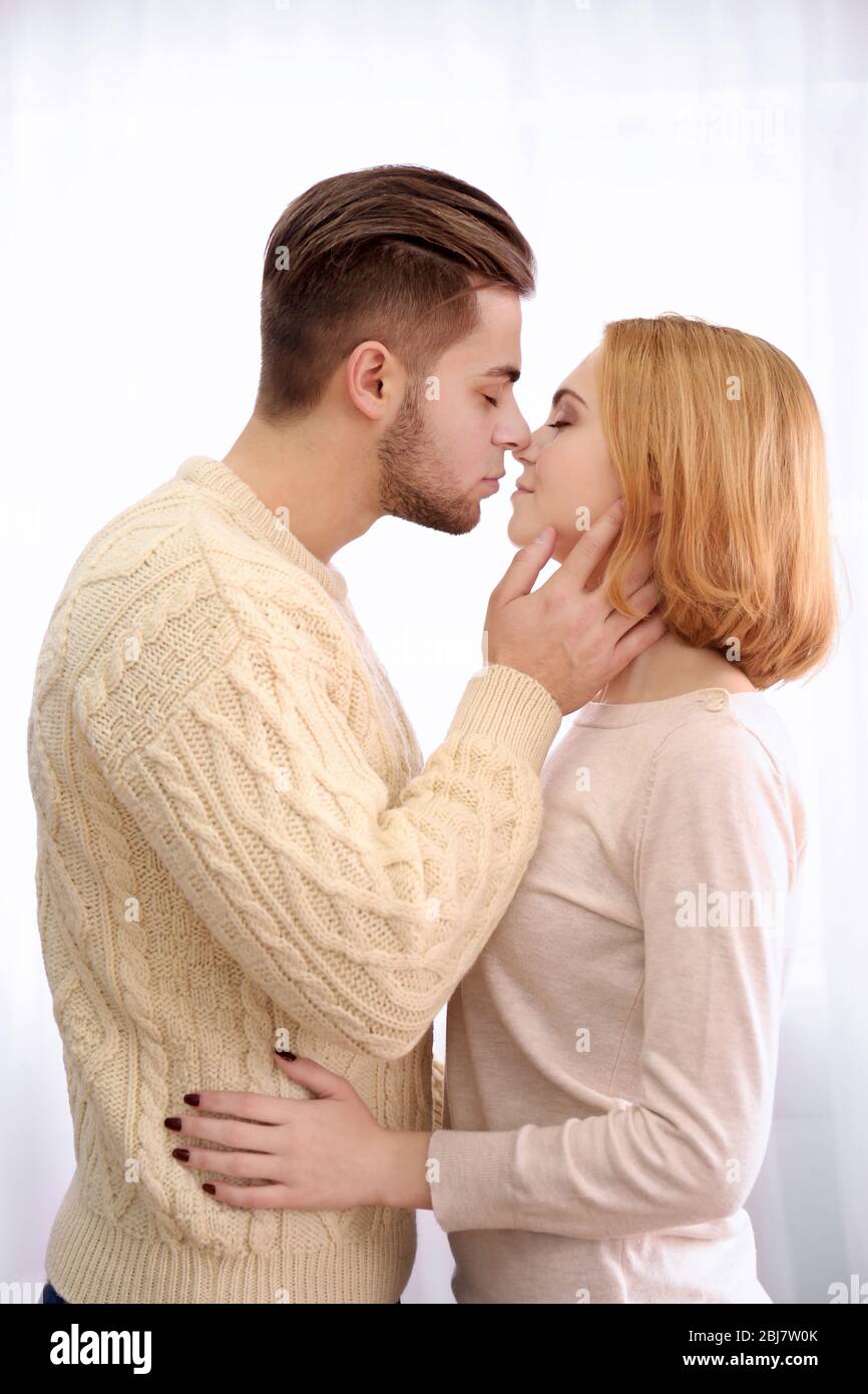 Young couple in love kissing on light background Stock Photo - Alamy