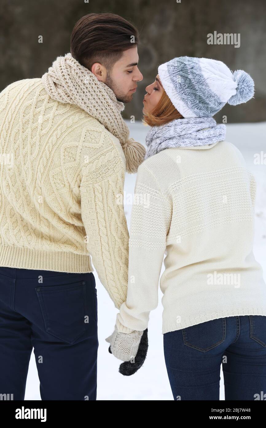 Young couple holding hands and kissing outdoors in winter Stock Photo