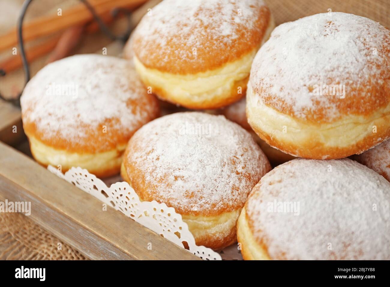 Delicious sugary donuts in wooden tray closeup Stock Photo