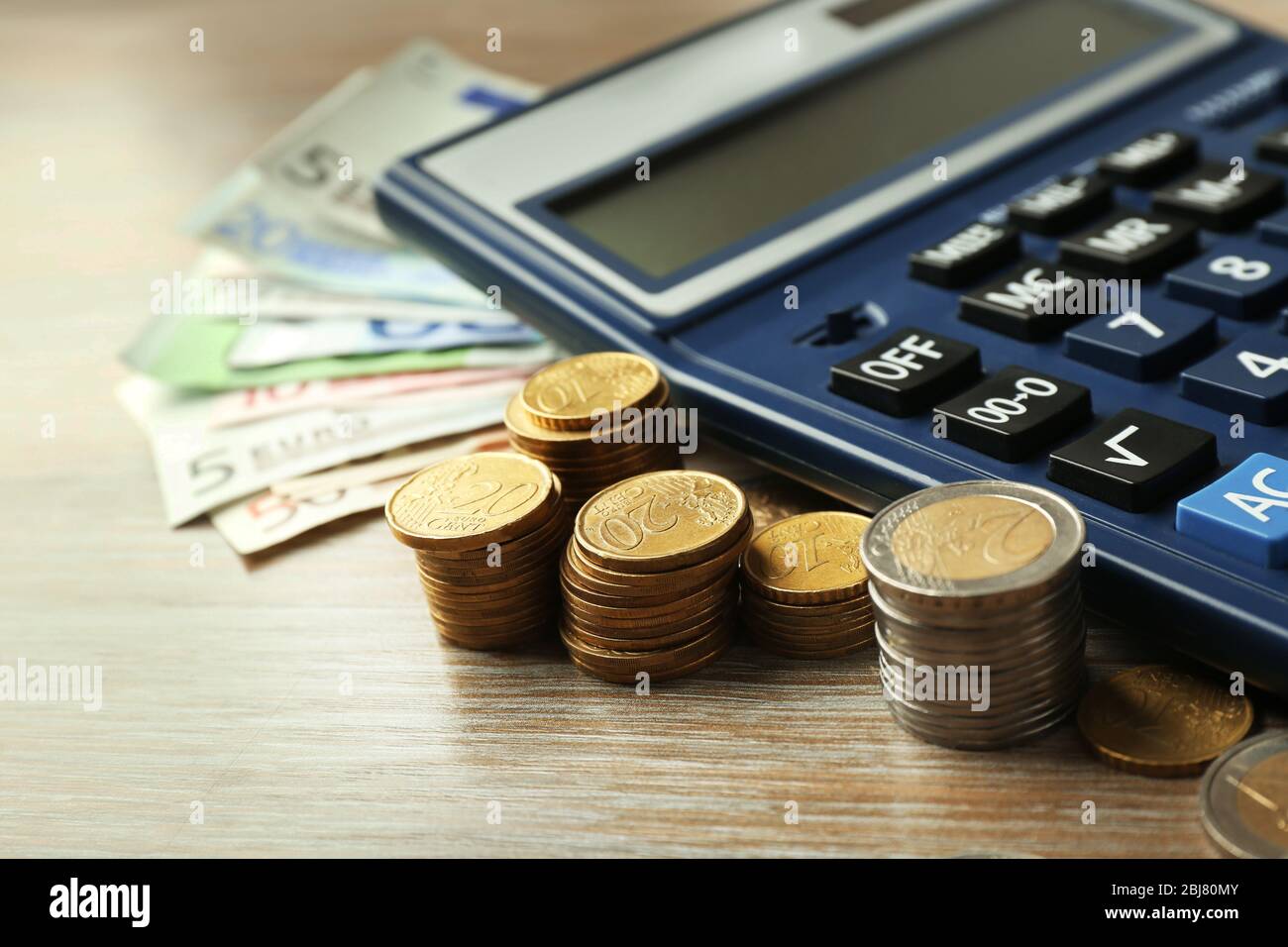 Money concept. Black calculator with banknotes and coins on wooden ...