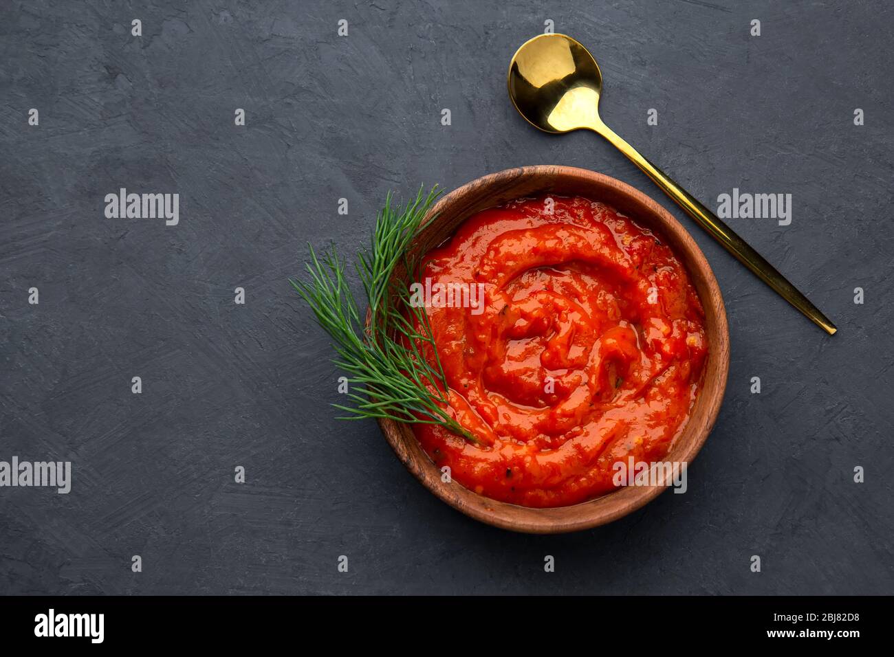 Traditional Balkan dish ajvar, lutenitza, pindjur on a dark background. Top view, place for text. Stock Photo