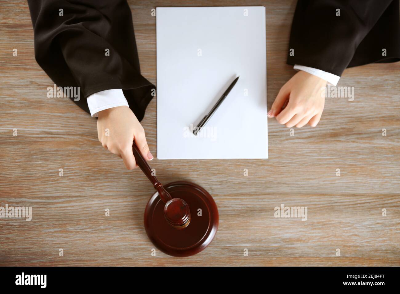 Judge hitting gavel with paper at wooden table, top view Stock Photo