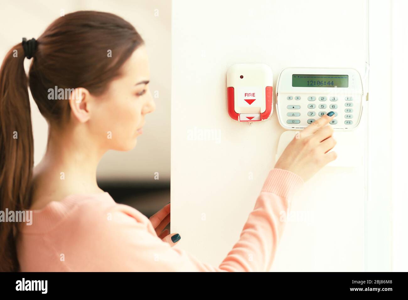 Woman pressing button on security system indoors Stock Photo
