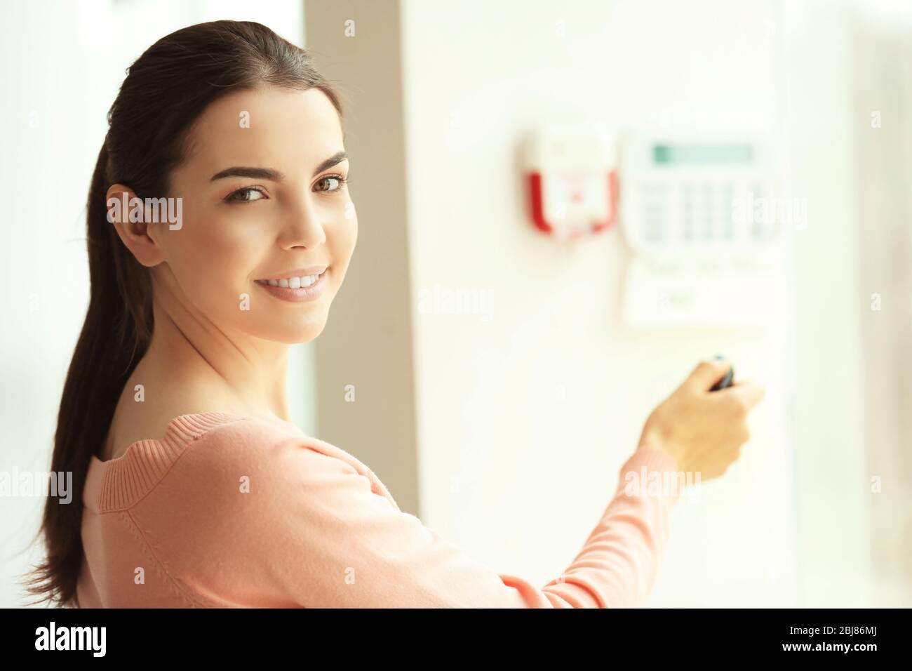 Woman pressing button on security system indoors Stock Photo