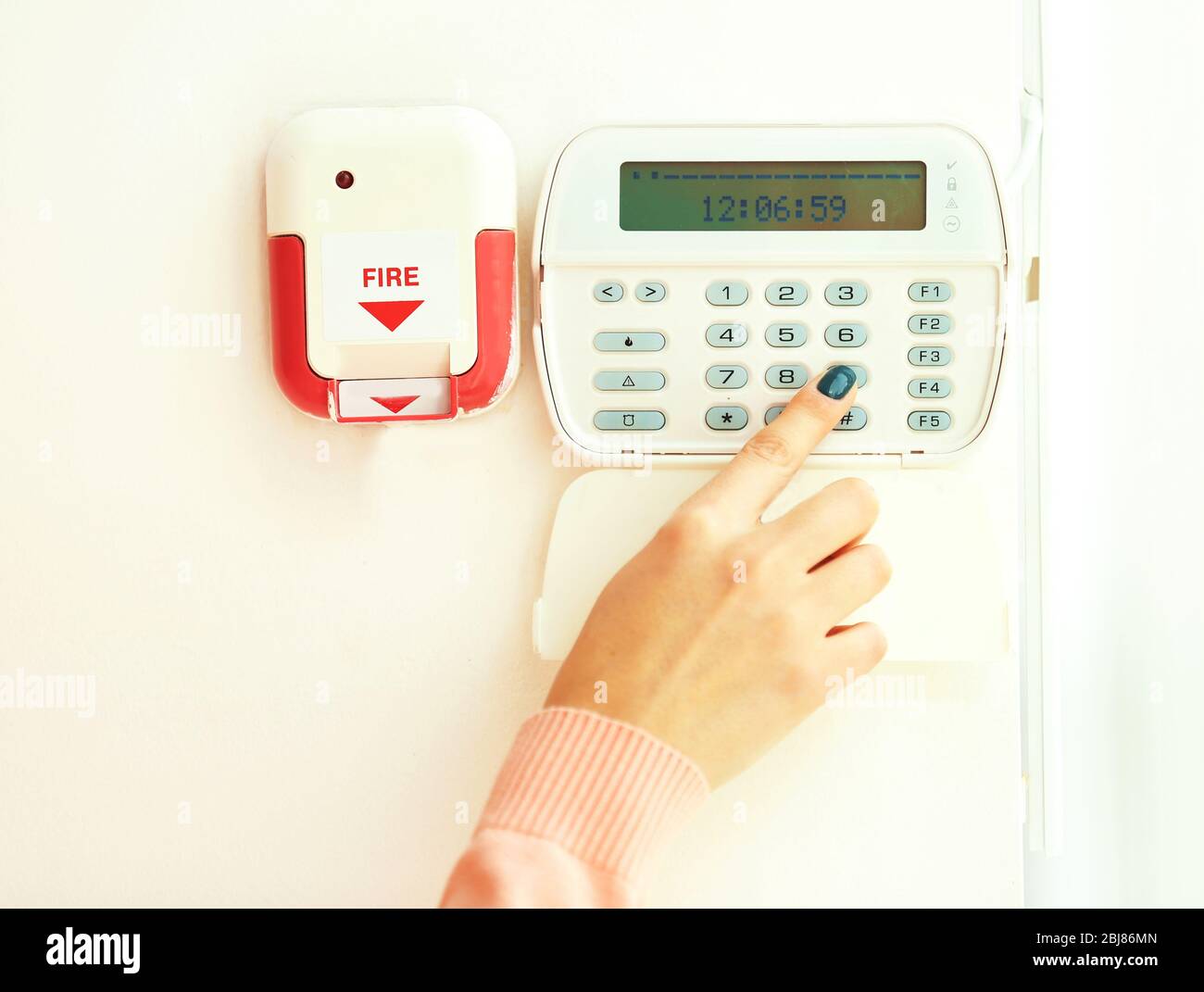 Woman pressing button on security system indoors Stock Photo
