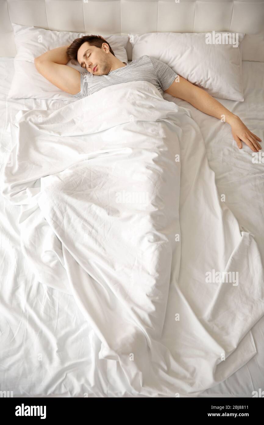 Young man sleeping alone in white big bed Stock Photo Alamy