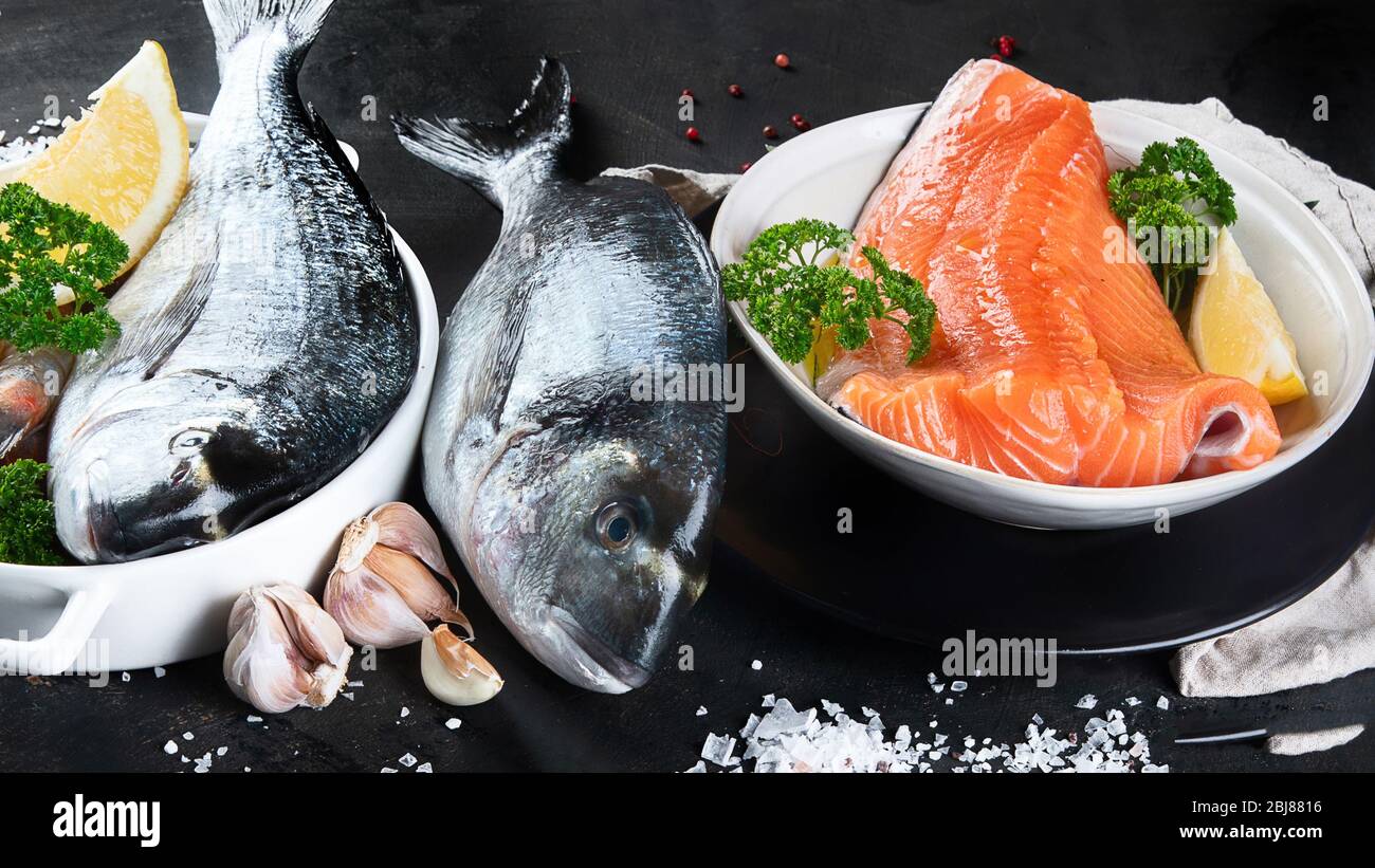 Fresh raw fish and seafood on black background. Stock Photo