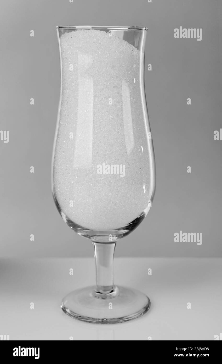Hurricane glass filled with granulated sugar on grey background Stock Photo
