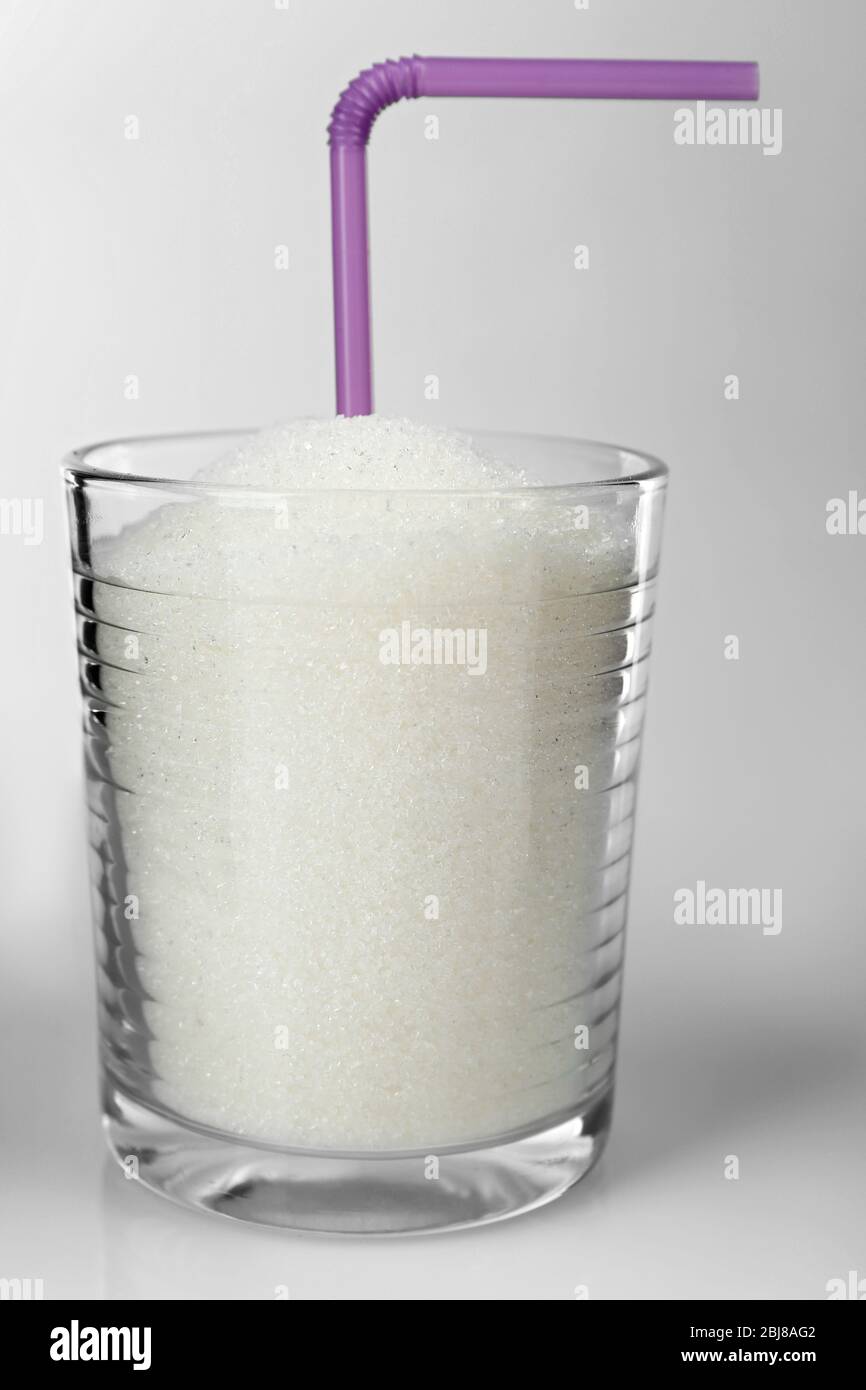 Old fashioned glass with granulated sugar and cocktail straw on grey