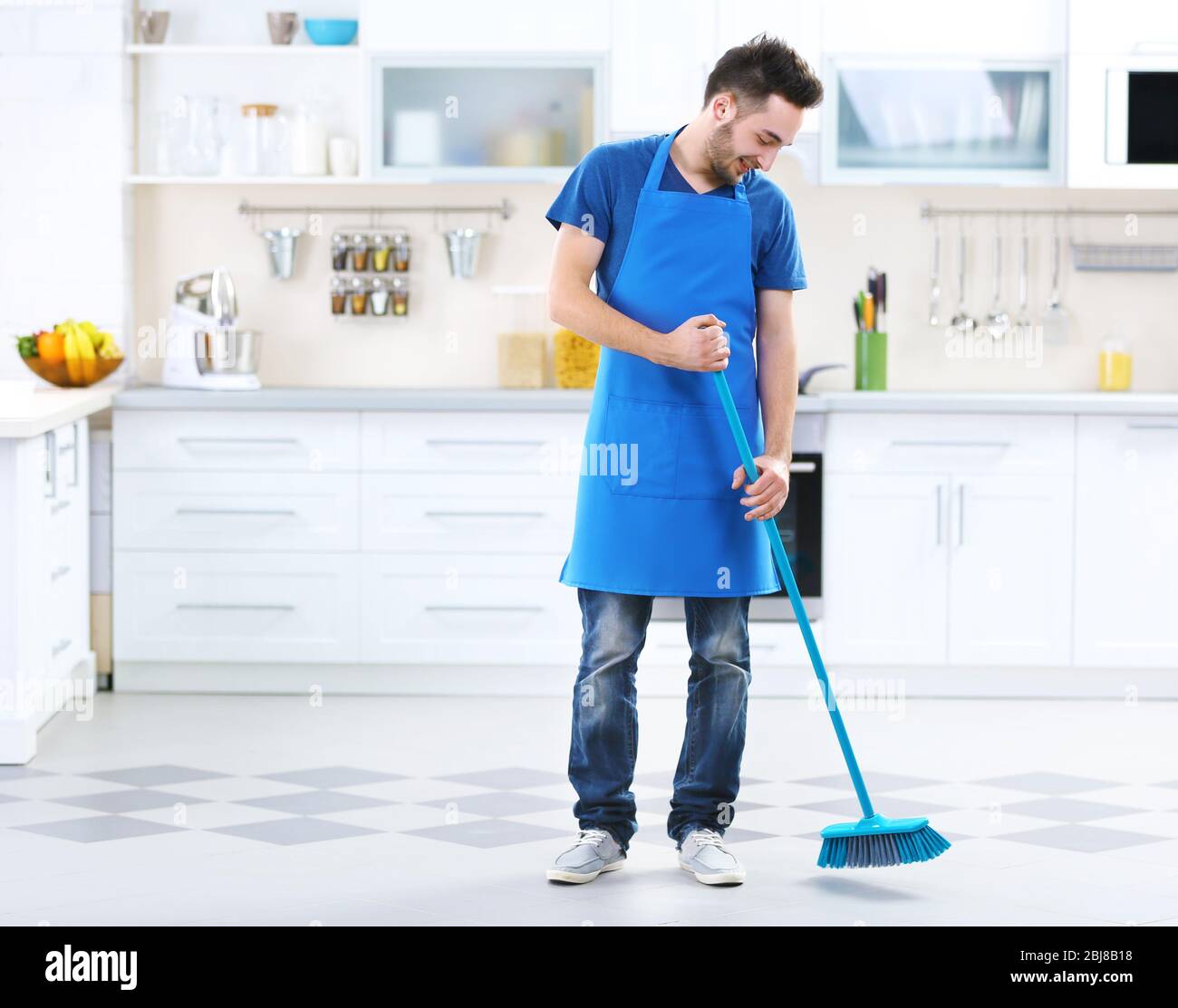 Man sweeping floor in the kitchen Stock Photo