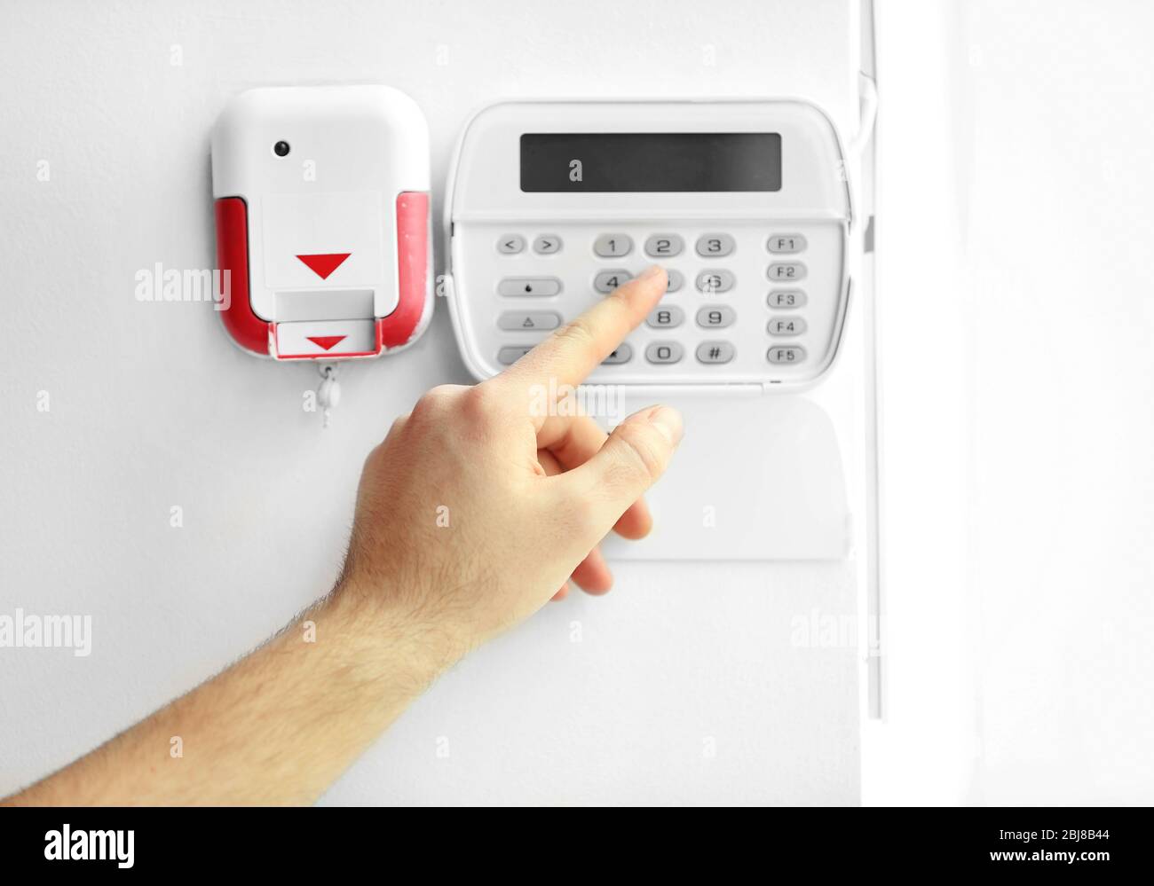 Male hand entering code on security system keypad indoors Stock Photo