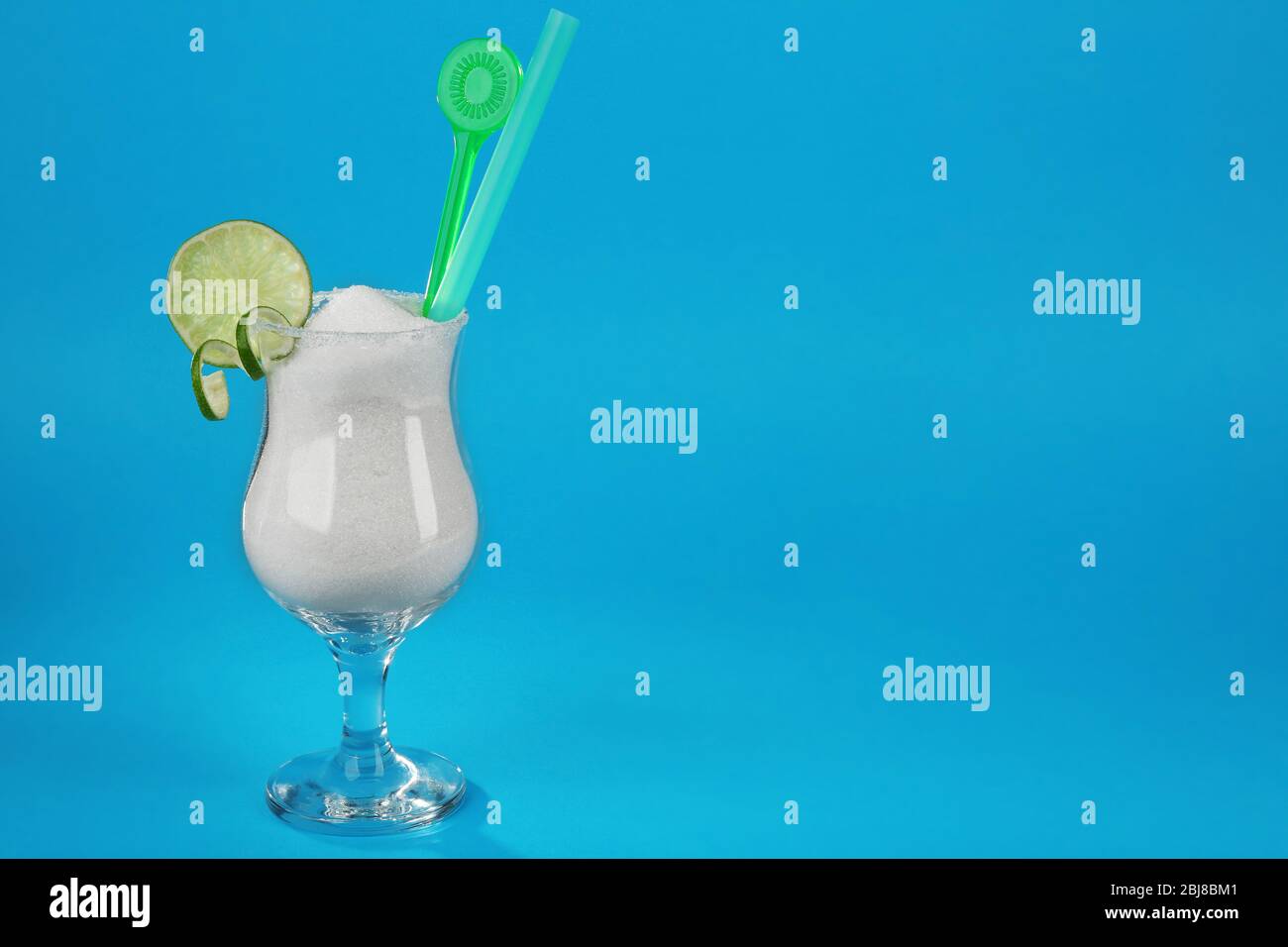 Hurricane glass with granulated sugar, cocktail tube and lime slice on