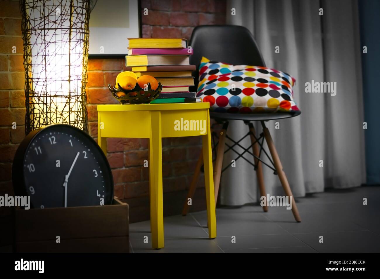 Stylish interior with yellow coffee table, books at night Stock Photo