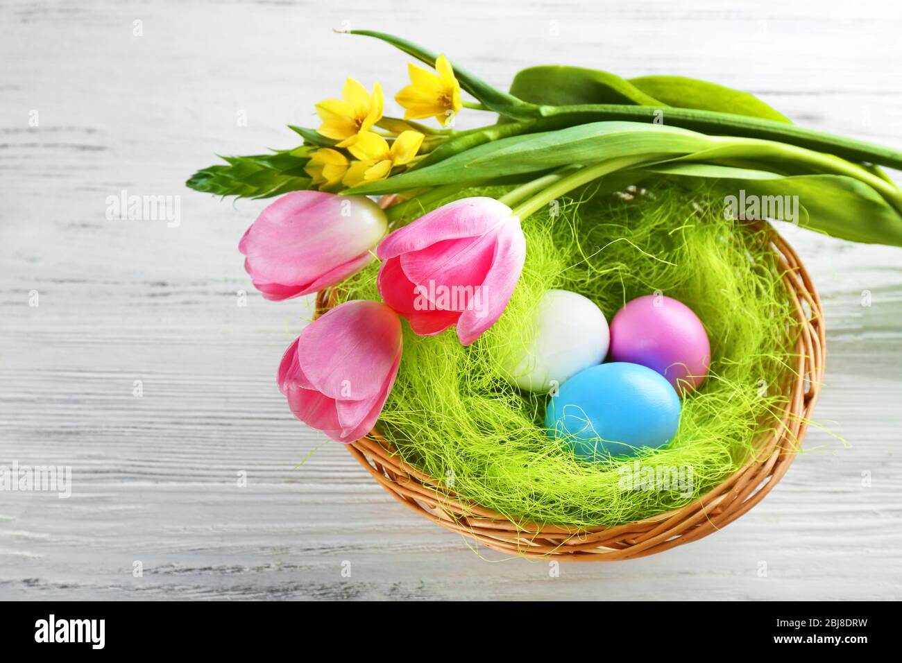 Easter eggs in nest with spring flowers on white wooden table Stock ...