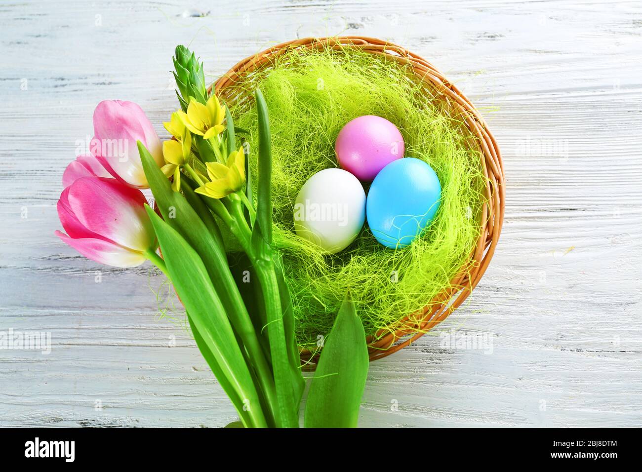 Easter eggs in nest with spring flowers on white wooden table Stock ...