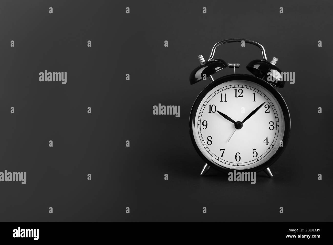 A retro alarm-clock on dark grey background. Stock Photo