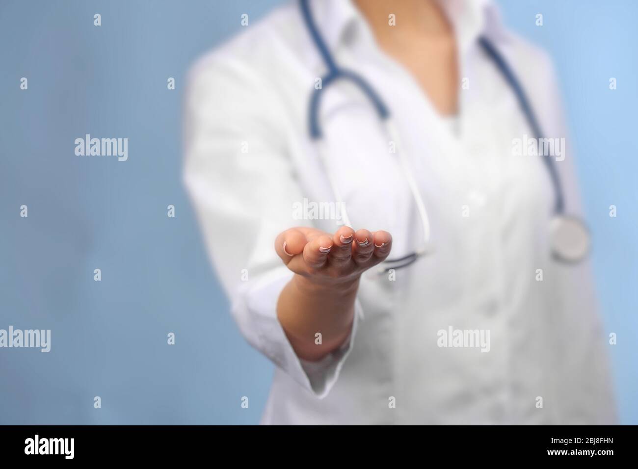 Young female doctor with outstretched hand and stethoscope Stock Photo