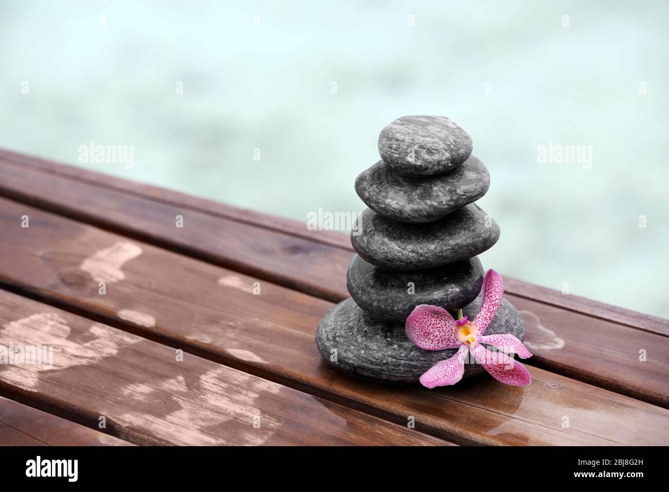 Stack of spa stones with pink orchid on wooden wet bridge Stock Photo ...