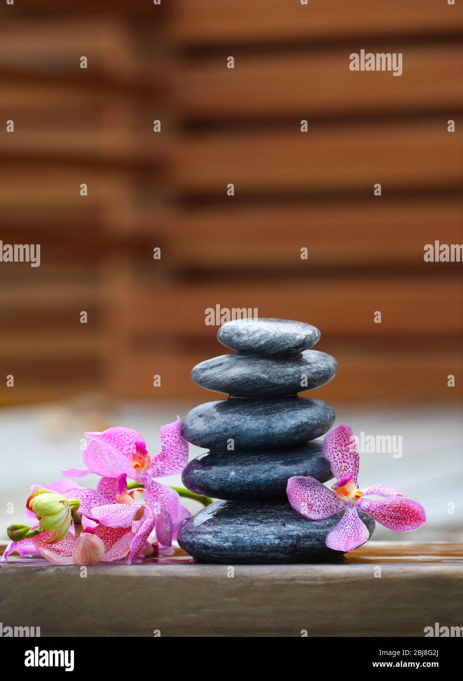 Stack of spa stones with pink orchids on wooden wet bridge Stock Photo ...