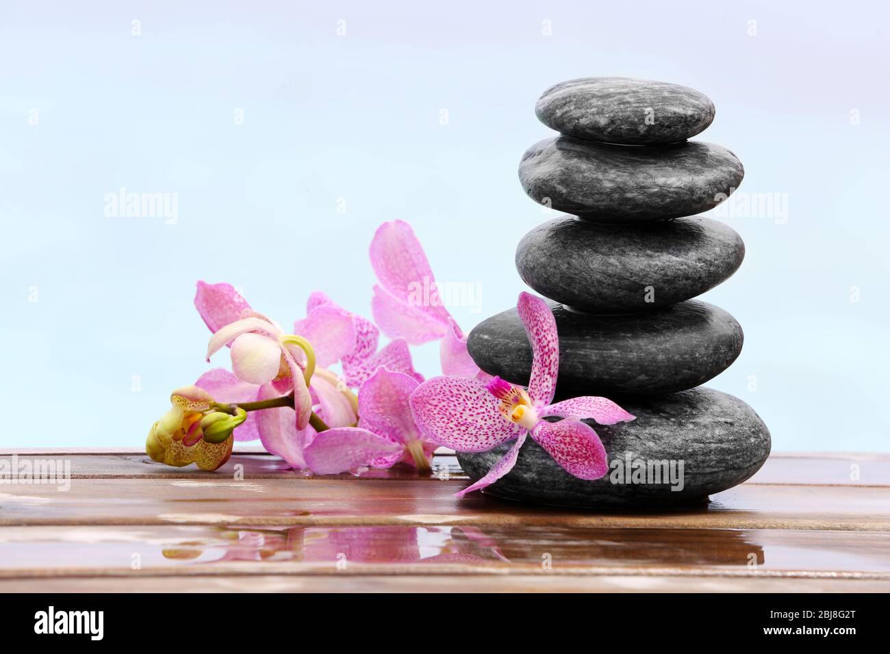 Stack of spa stones with pink orchids on wooden wet bridge Stock Photo ...