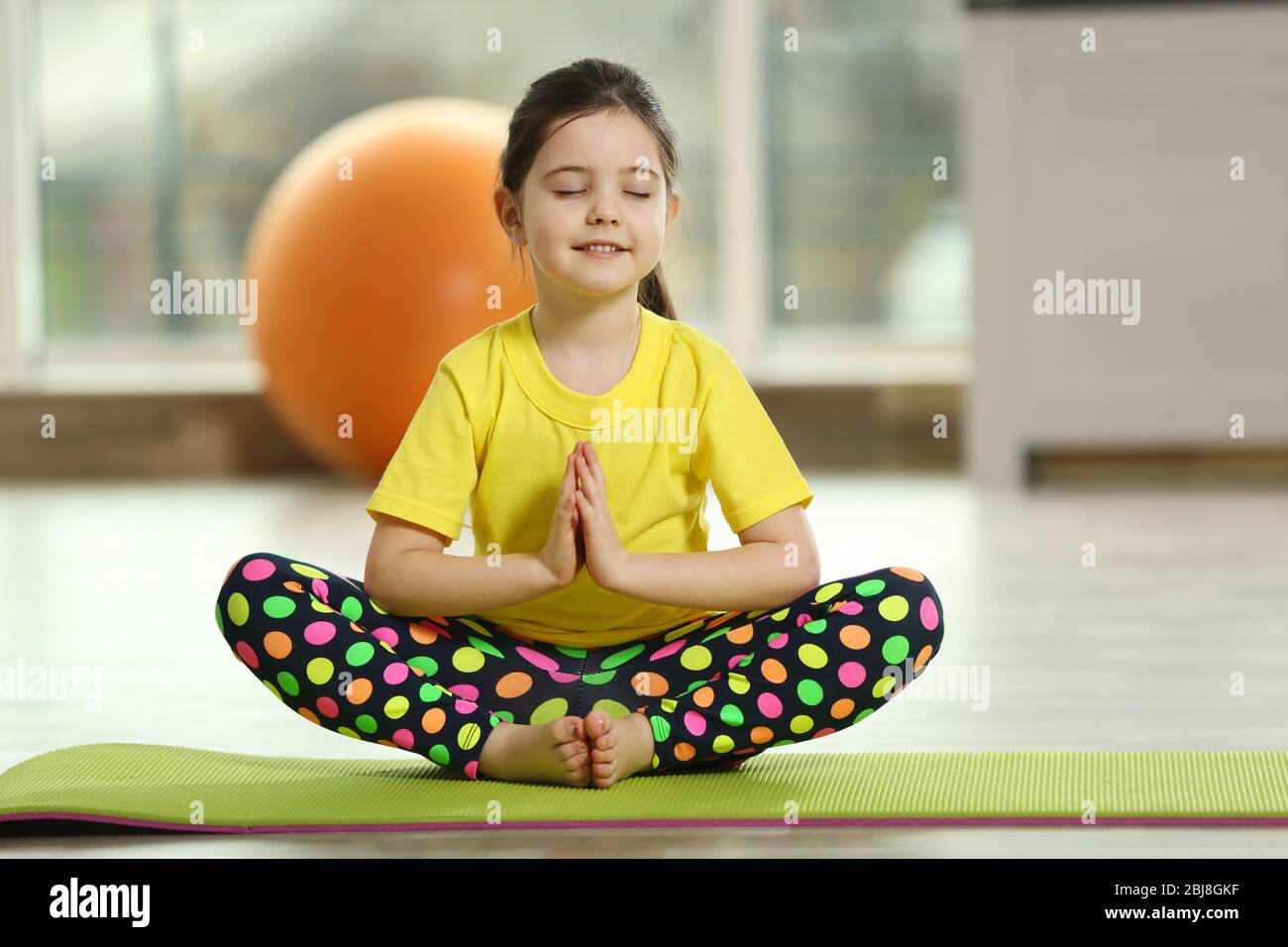 Little cute girl practicing yoga pose on a mat indoor Stock Photo - Alamy
