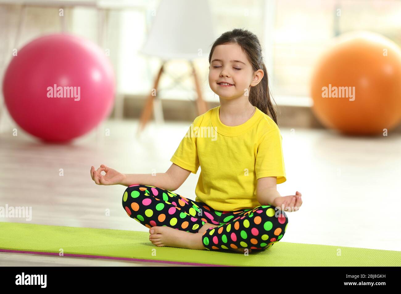Little cute girl practicing yoga pose on a mat indoor Stock Photo - Alamy