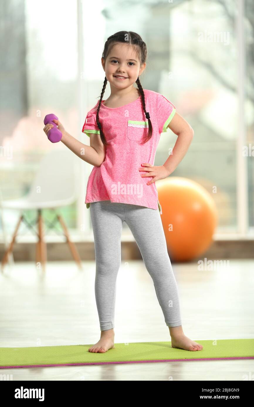 Little cute girl doing exercises with dumbbells on a mat indoor Stock ...