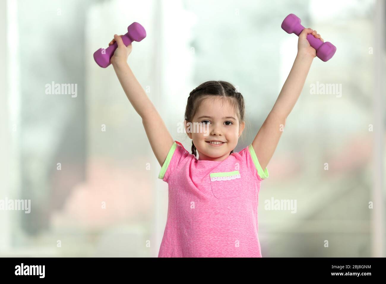 Little cute girl doing exercises with dumbbells indoor Stock Photo - Alamy