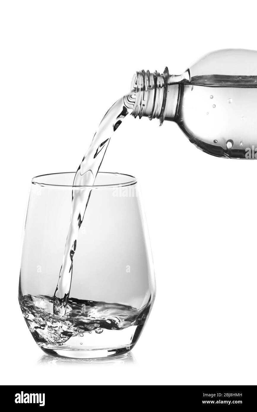 Pouring water from bottle into glass over grey background Stock Photo