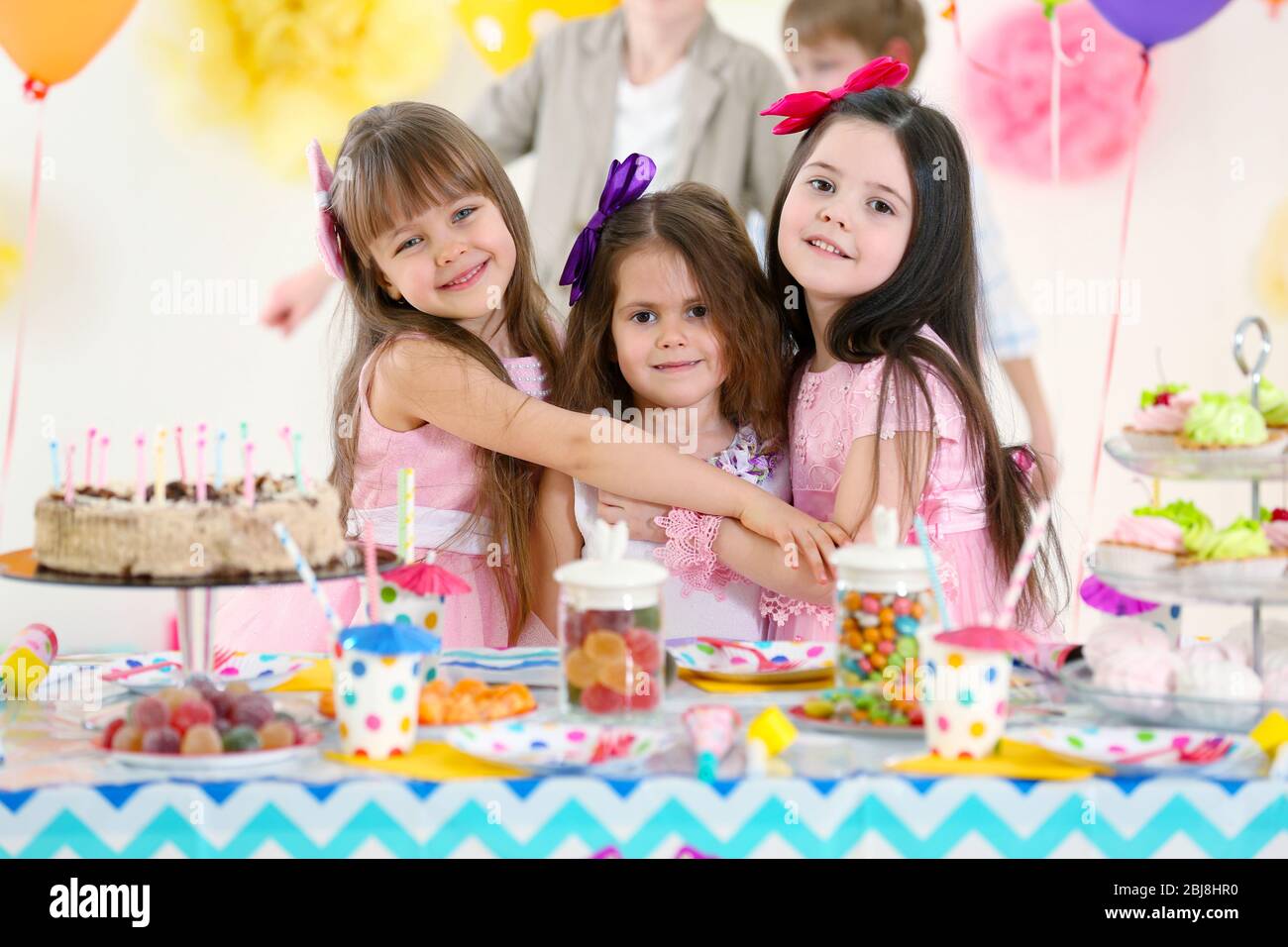 Happy little girls hugging at birthday party Stock Photo - Alamy